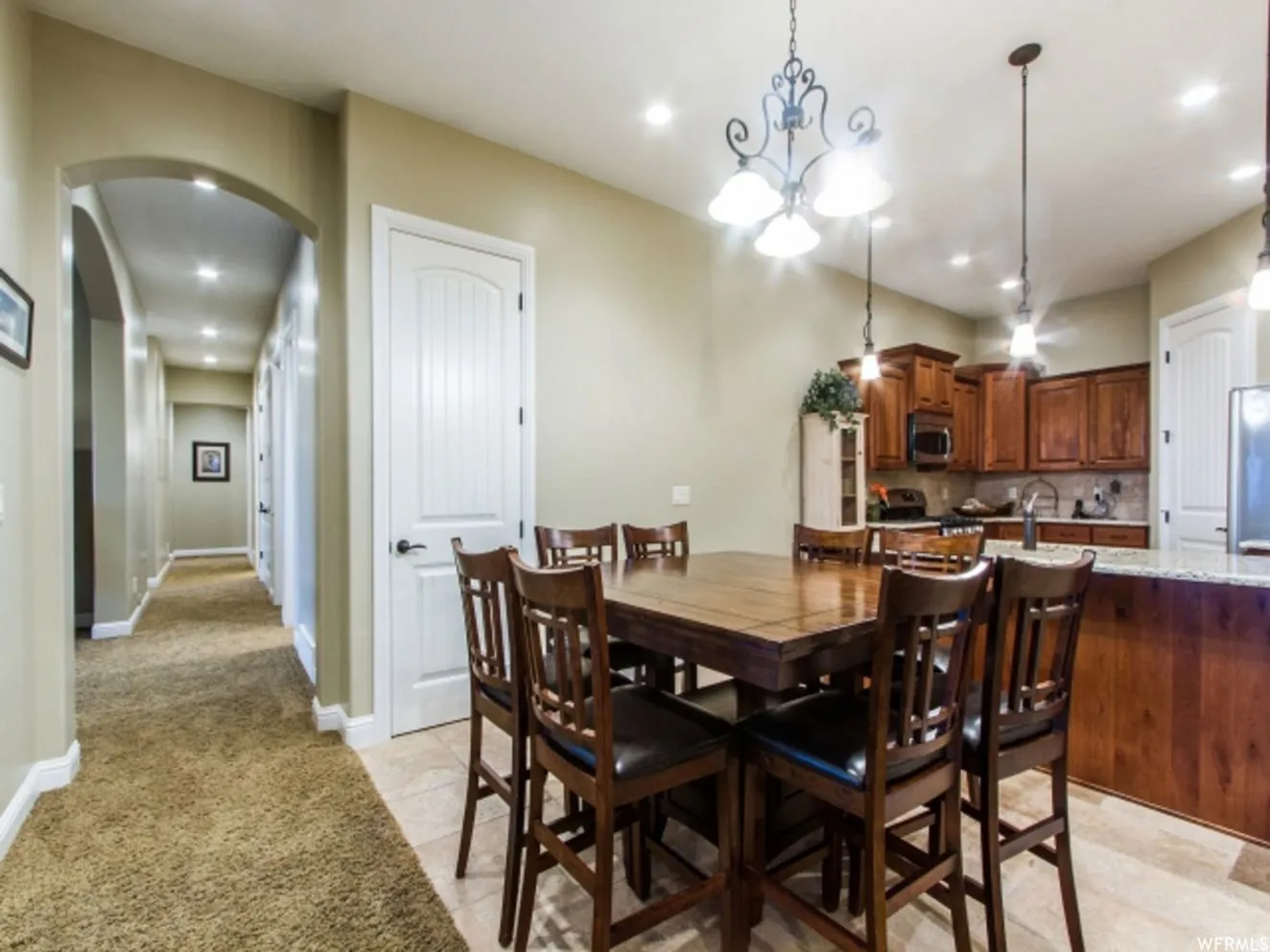 Kitchen and dining area featuring wood-finish cabinetry, a stone-finish countertop, and tile flooring