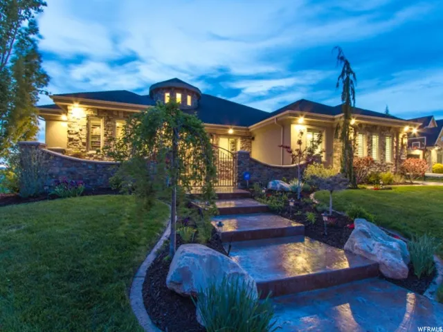 Stone and stucco exterior featuring a prominent turrret, stamped concrete steps, and a wrought iron gate
