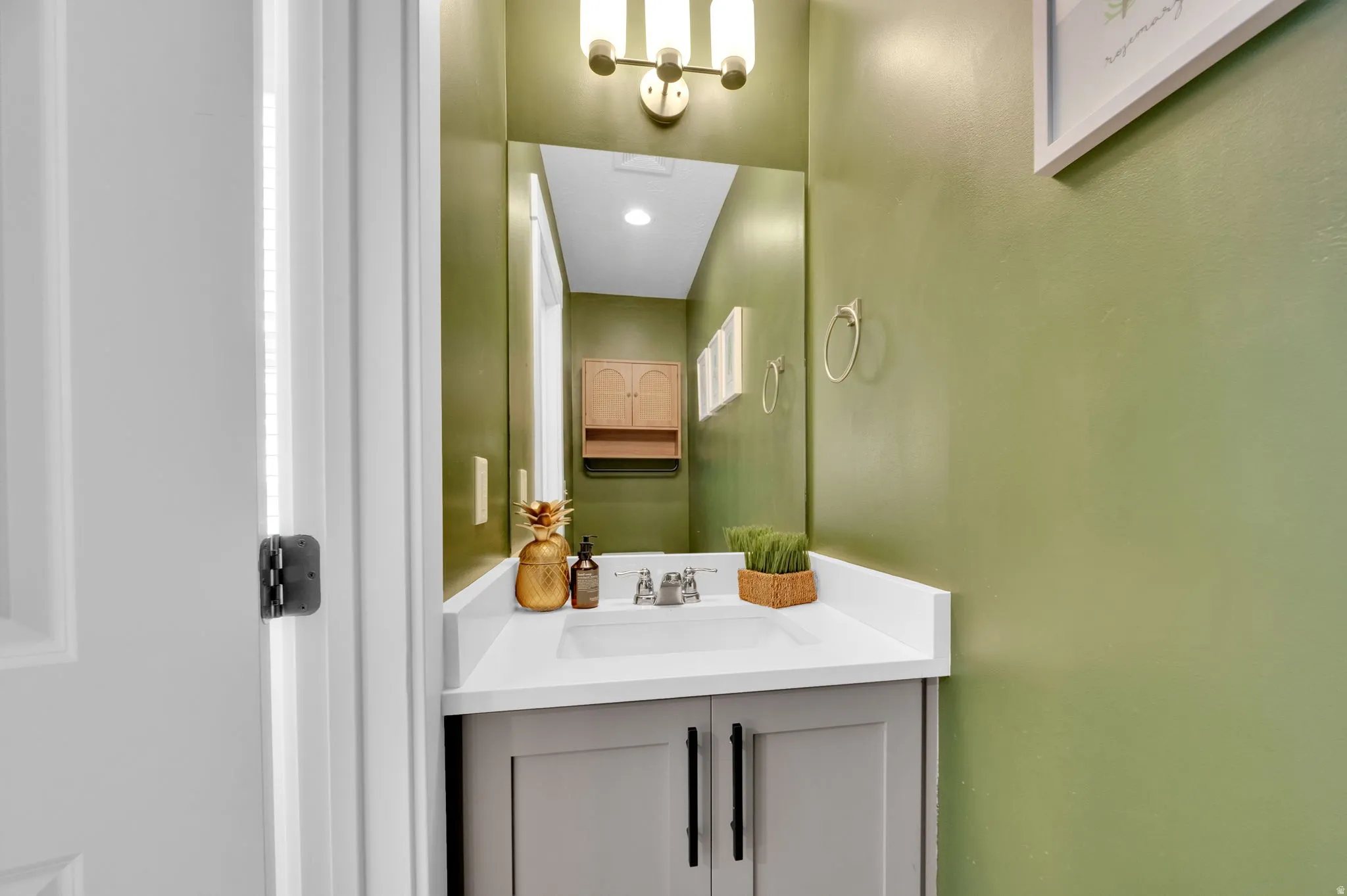 Bathroom vanity featuring a white countertop, undermount sink, and gray cabinetry with dark hardware