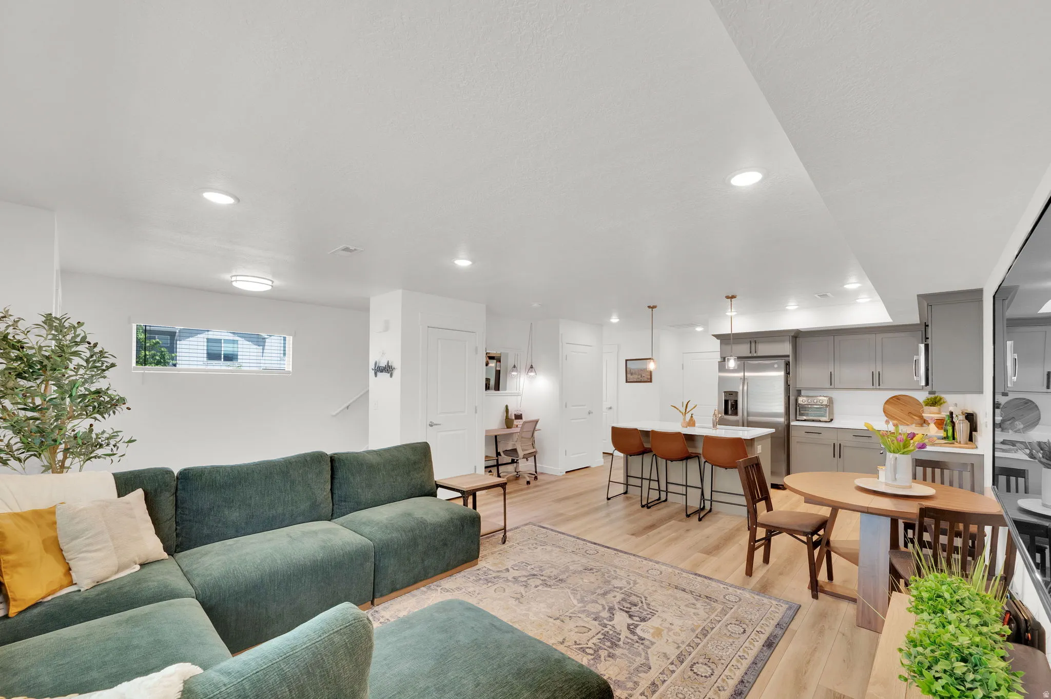 Open-concept living area featuring light wood-finish flooring, recessed lighting, and a white color palette