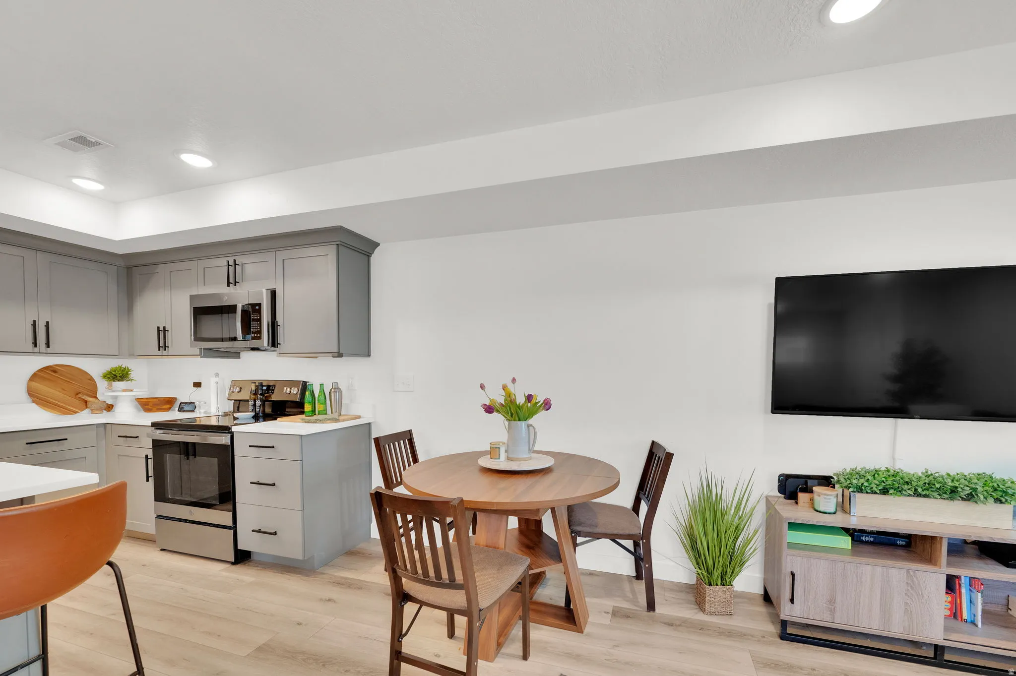 Modern kitchen featuring gray cabinetry, stainless steel appliances, white subway tile backsplash, and light wood-finish flooring