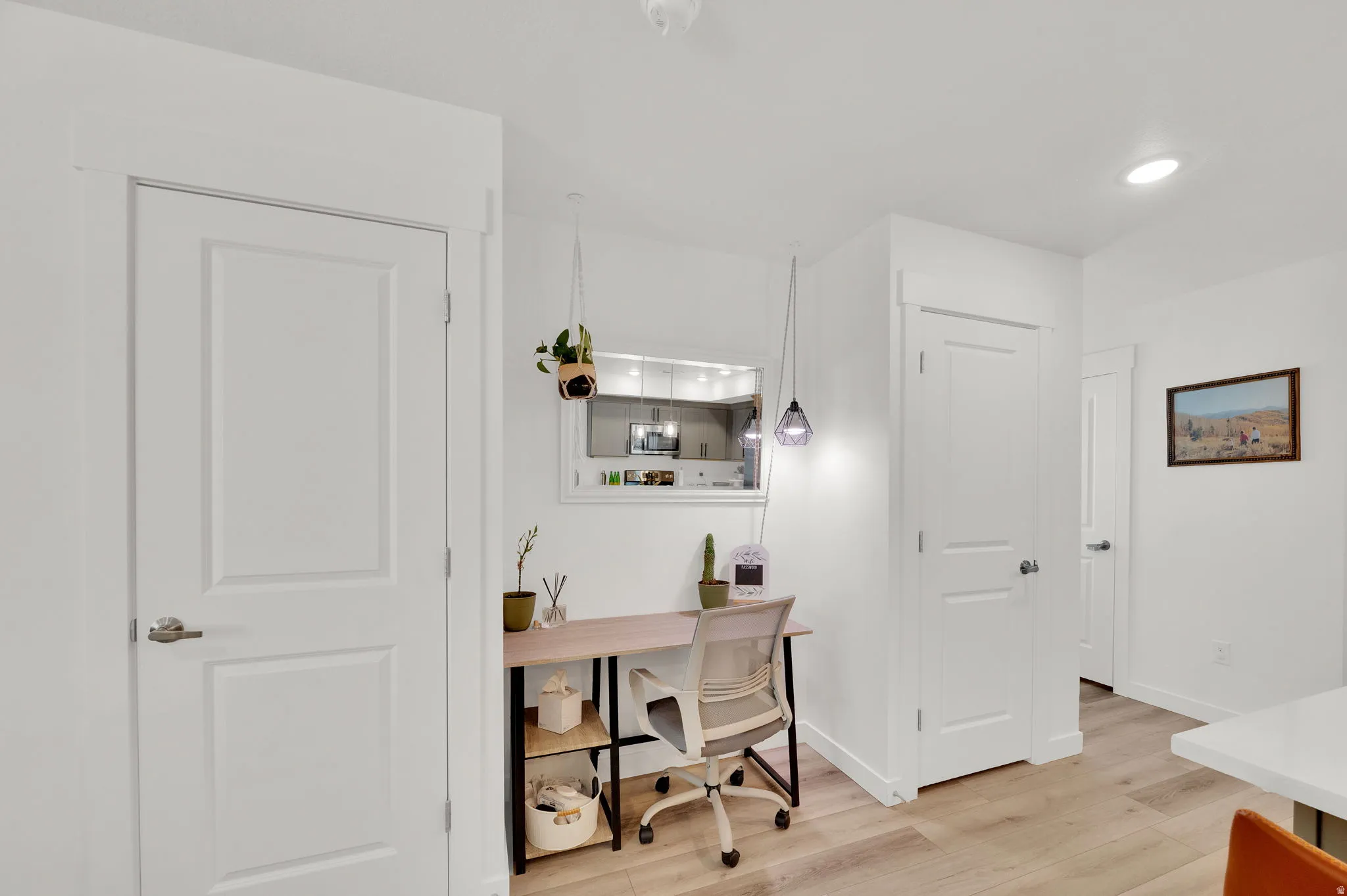 Dedicated workspace featuring a built-in desk, wood-finish flooring, and crisp white walls