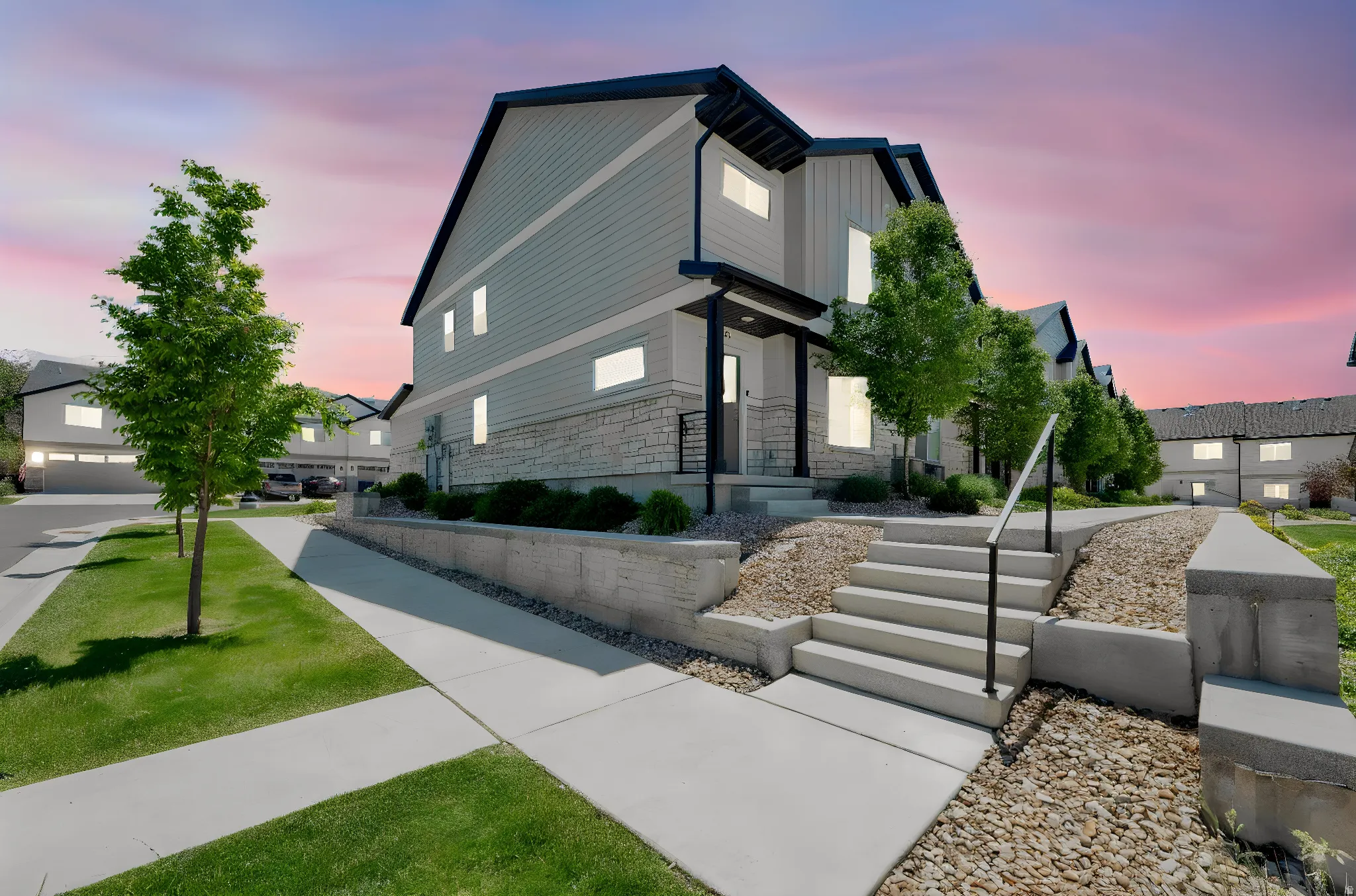 Contemporary multi-level residence featuring light-colored siding, stone veneer accents, and a dark-trimmed roofline