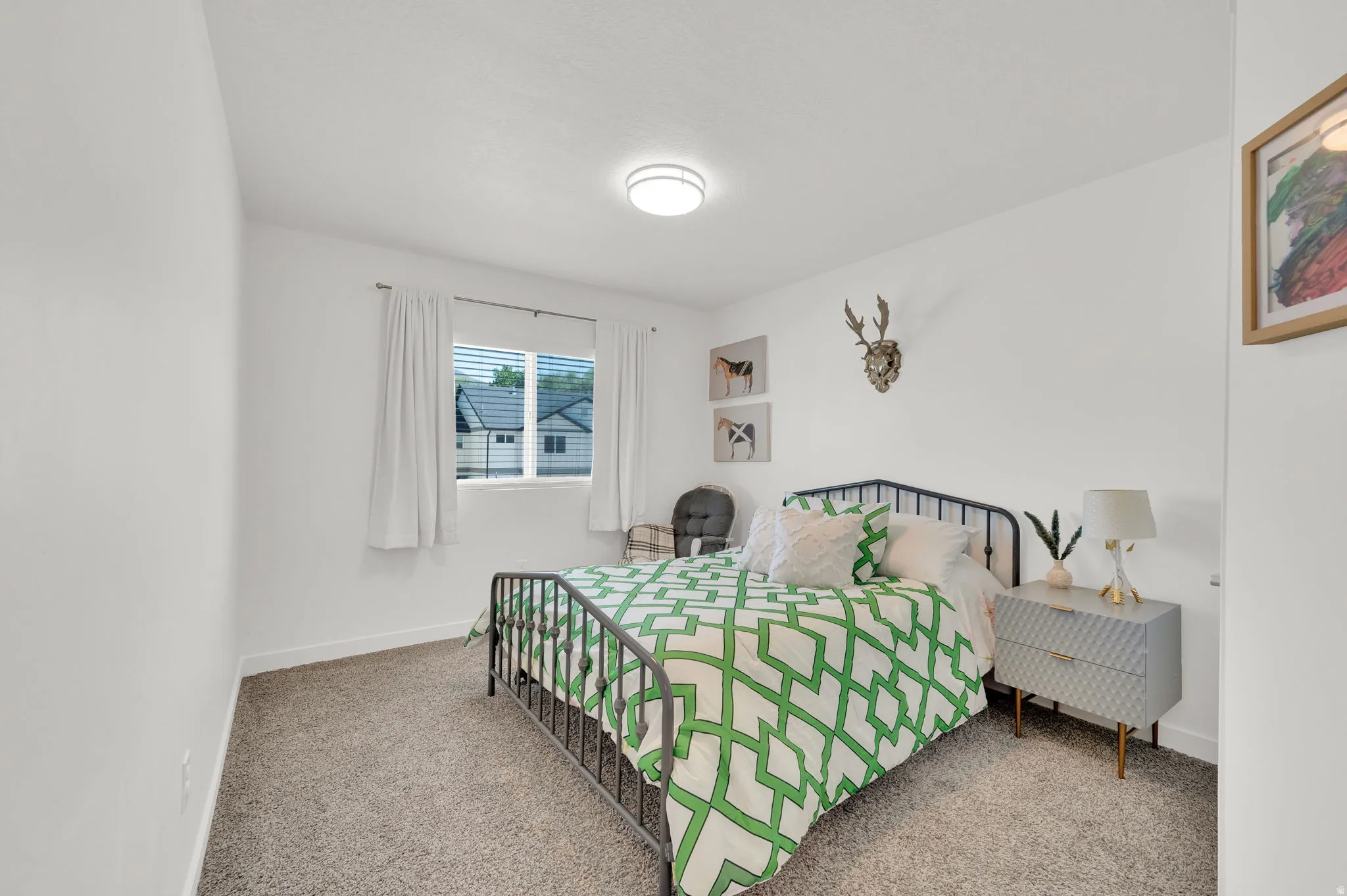 Bright interior space featuring a window with horizontal blinds, neutral wall paint, and a textured carpeted floor