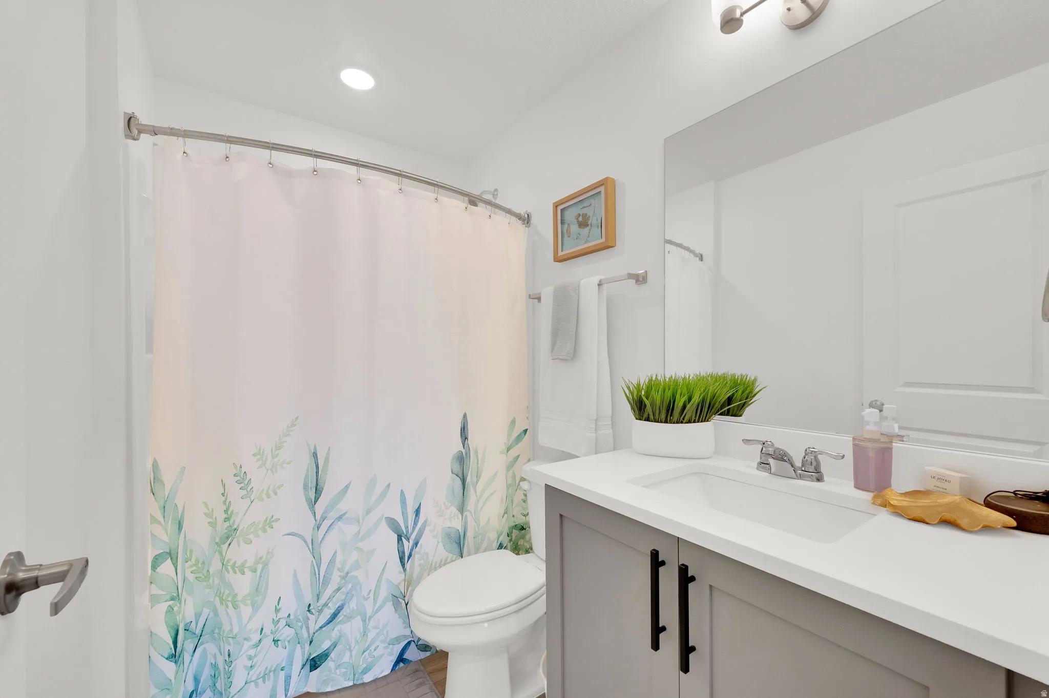 Full bathroom featuring a single vanity with a white countertop and gray cabinetry, an undermount sink with a chrome faucet, and a toilet