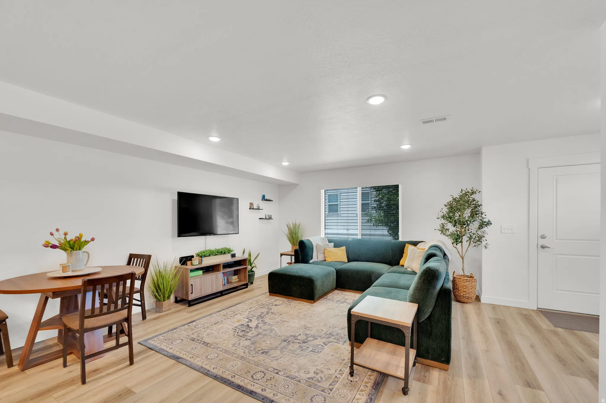 Open-concept living area featuring light wood-finish flooring, recessed lighting, and white baseboards