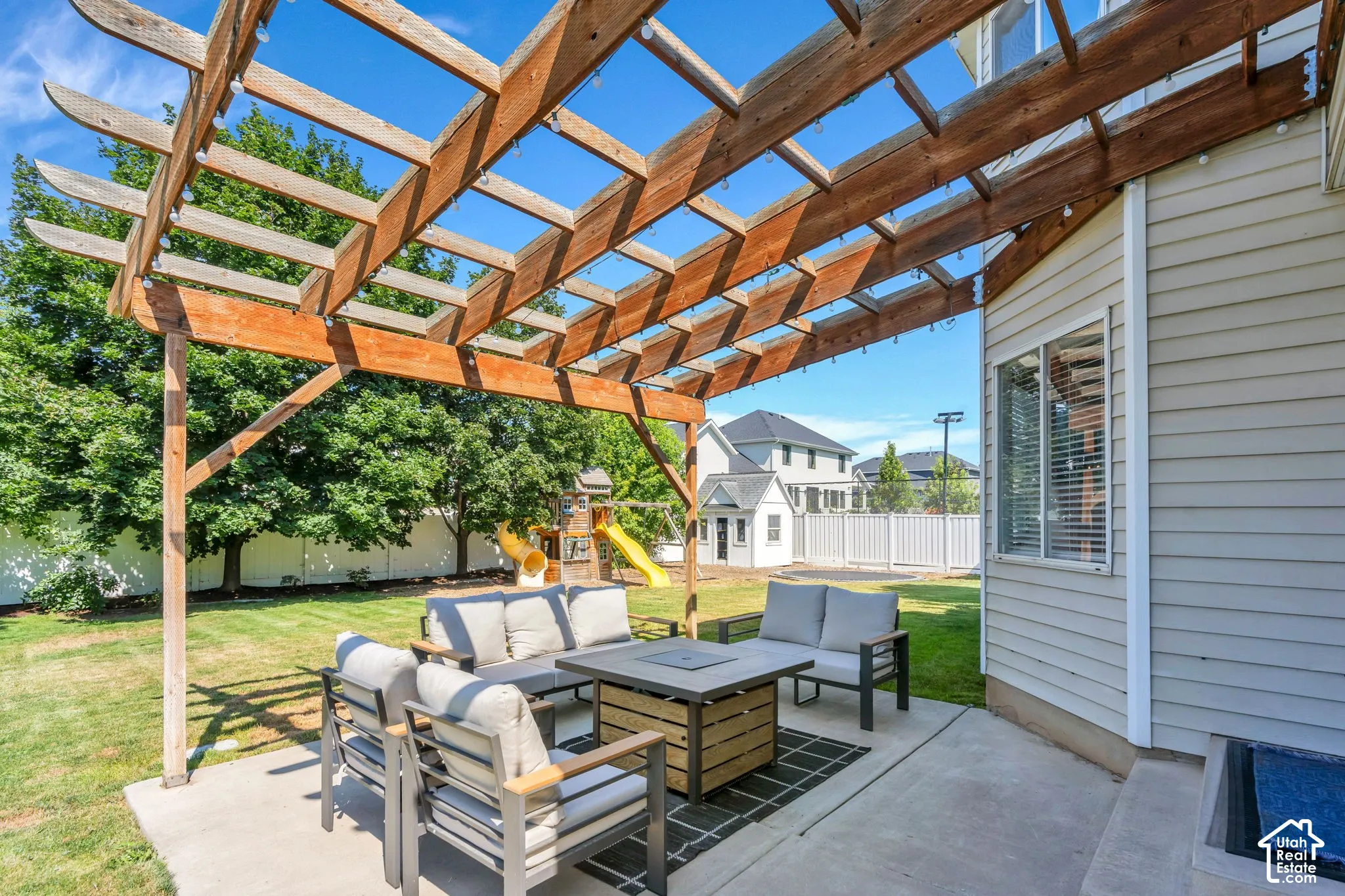 Concrete patio featuring a custom wood pergola, siding exterior, and fenced backyard with mature trees