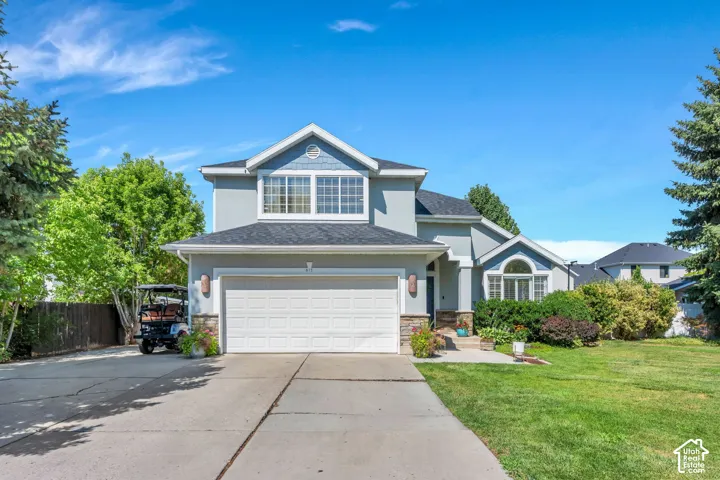 Contemporary two-story residence featuring a light gray exterior with stone accents and a prominent two-car garage