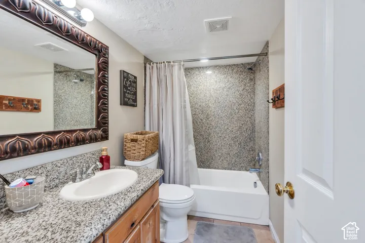 Bathroom featuring a vanity with a granite-style countertop, an oval undermount sink, and a framed mirror