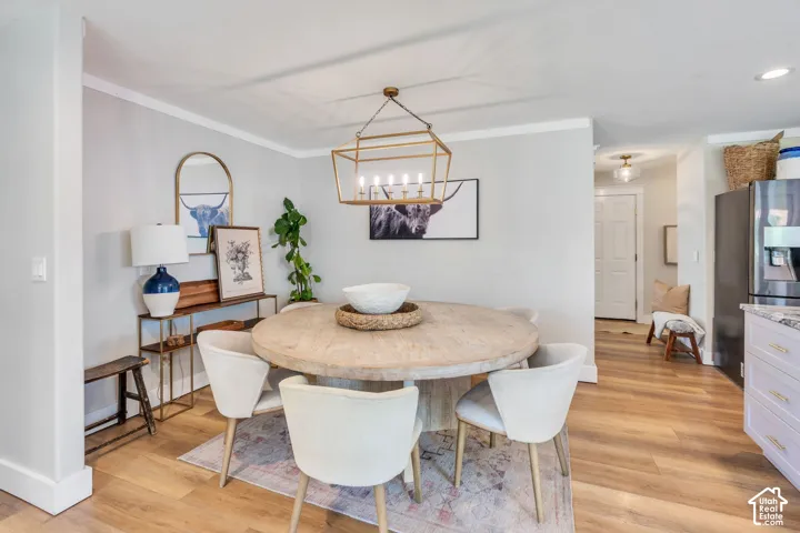 Dining area featuring wood-finish flooring, a round table, and a linear chandelier