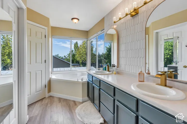 Bathroom featuring a dual vanity with gold-tone fixtures, oval sinks, and a large countertop