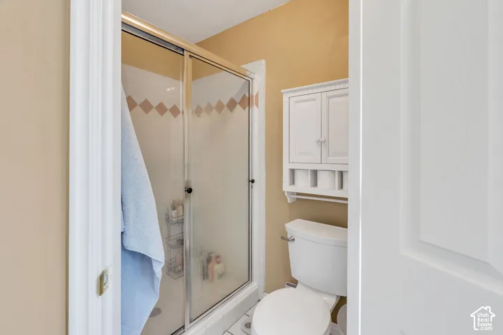 Walk-in shower featuring a gold-tone framed sliding glass door and white ceramic tile with diamond accents