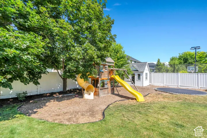 Expansive backyard featuring a manicured lawn, white privacy fencing, and mature trees providing shade
