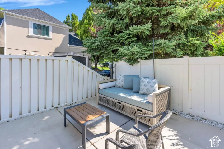 Private patio space with concrete flooring, white privacy fencing, string lighting, and gravel landscaping
