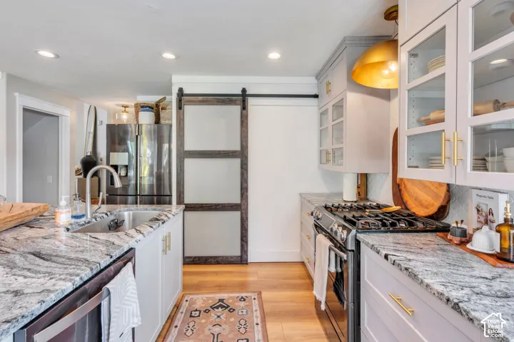 Kitchen featuring wood-finish flooring, light-toned cabinetry with gold-tone hardware, and granite countertops