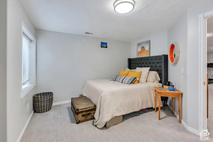 Well-lit room featuring light gray walls, white trim, a recessed window with blinds, light-toned carpeting, and a flush mount ceiling light fixture