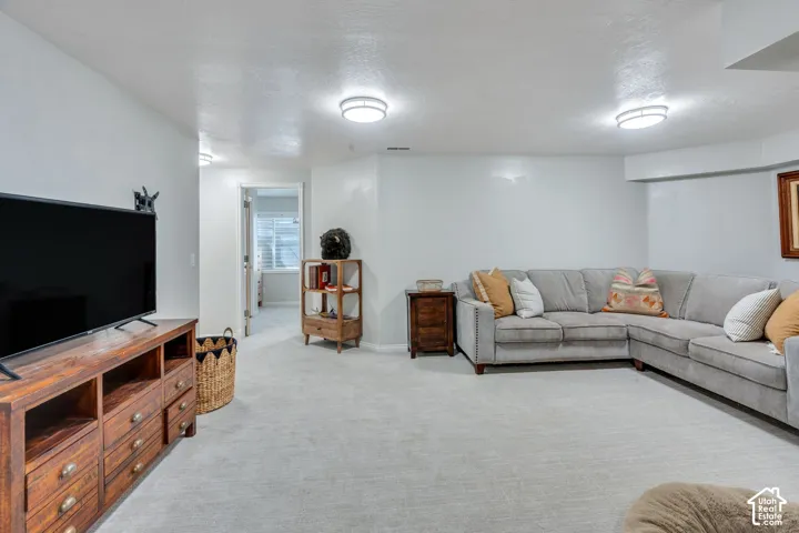 Spacious carpeted living area with light-toned walls and ceiling-mounted lighting