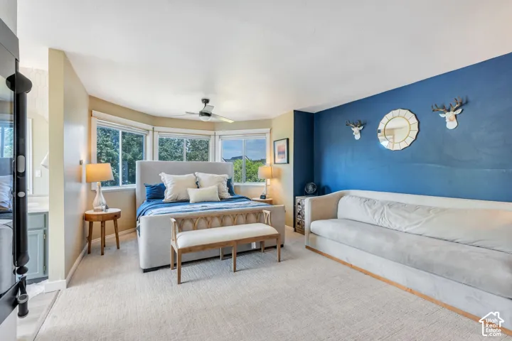 Expansive room featuring a bay window, ceiling fan, and carpeted flooring