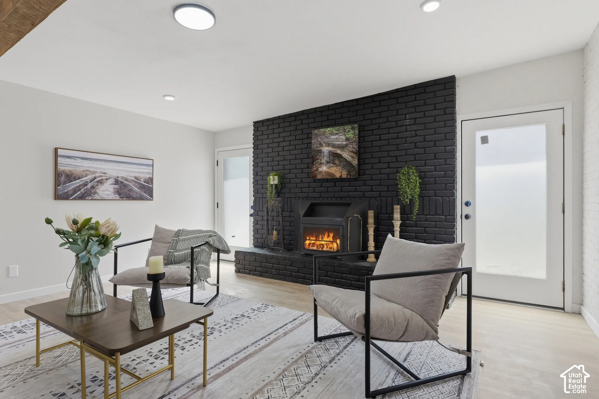 Living space featuring a black brick fireplace, wood-finish flooring, and recessed lighting