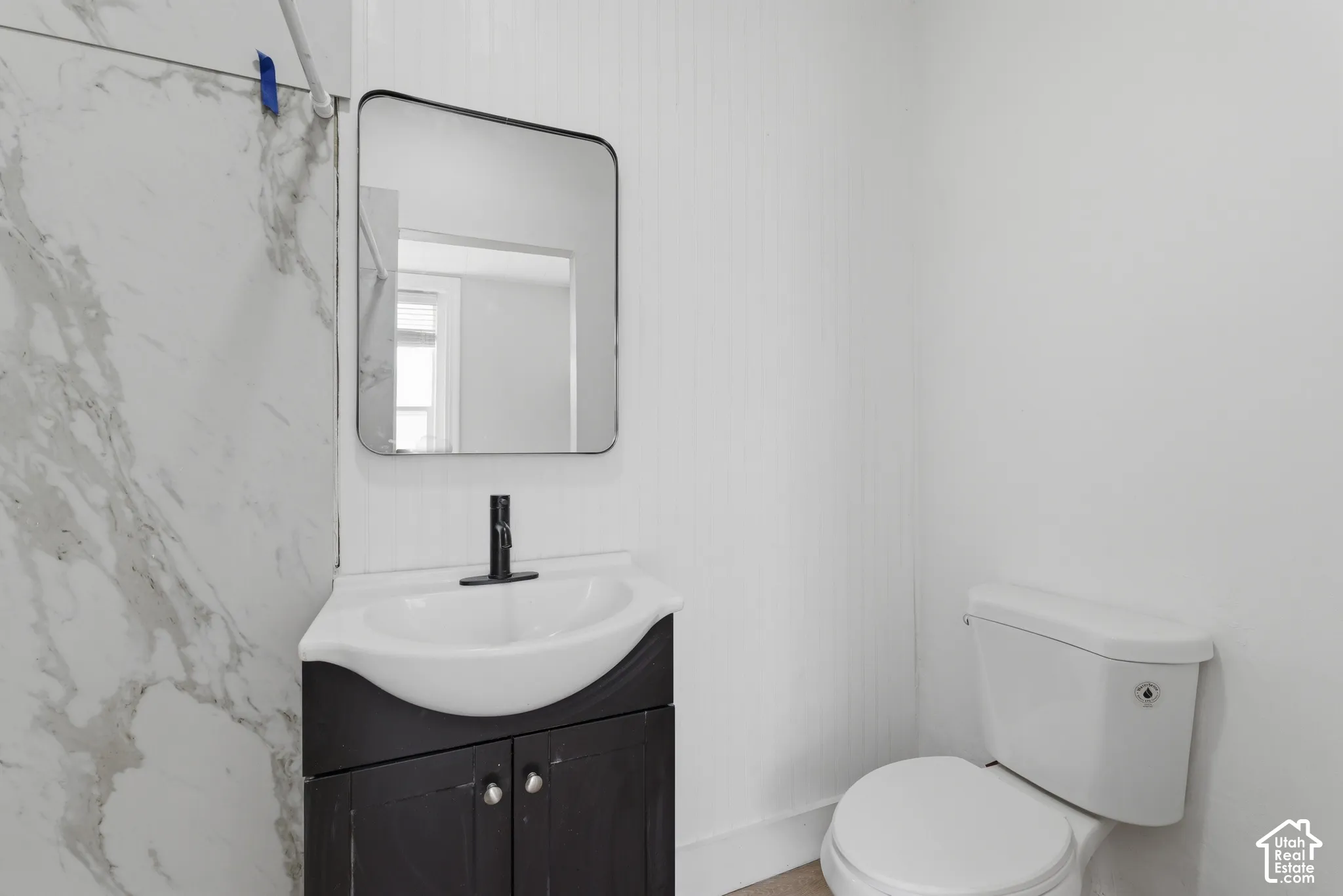 Modern bathroom vanity featuring a black cabinet, white countertop with integrated sink, and matte black faucet
