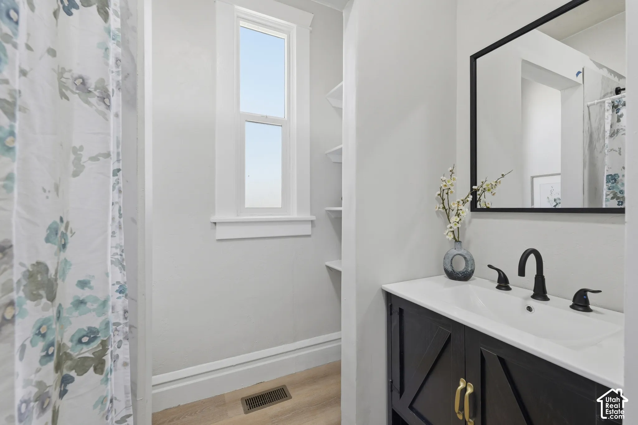 Bathroom featuring a black vanity with a white countertop, inset sink, and matte black faucet
