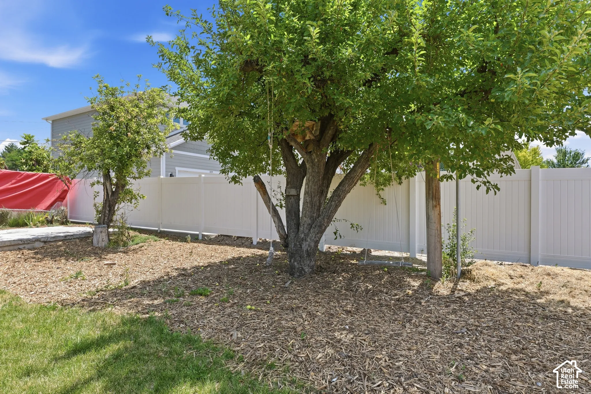 Backyard featuring established trees and a white privacy fence