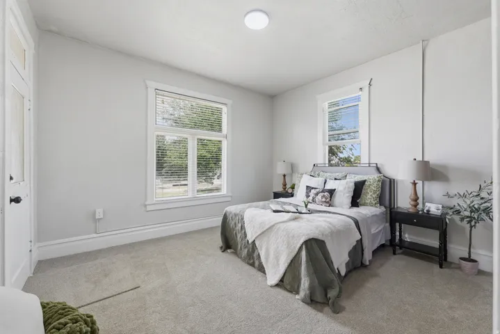 Carpeted room featuring multiple windows with blinds, a white paneled door, and a flush-mount ceiling light fixture