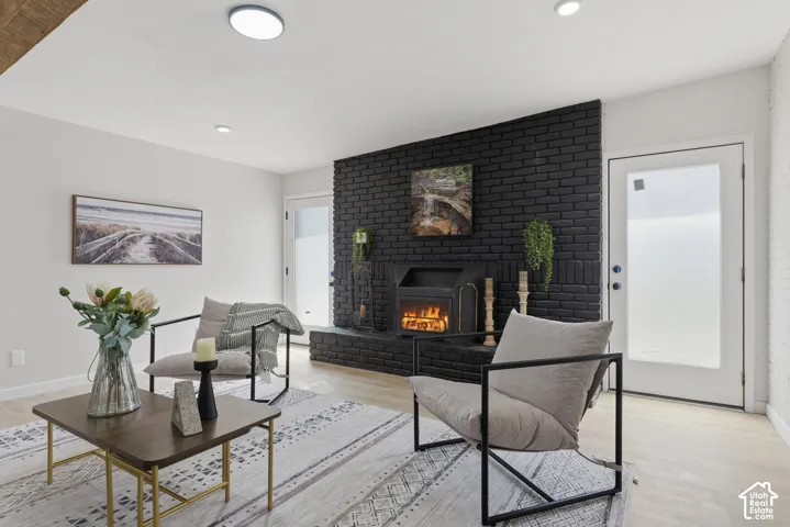 Living space featuring a black brick fireplace, wood-finish flooring, and recessed lighting