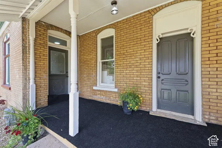 Brick facade featuring an arched entryway with decorative trim, a paneled door, and a covered porch