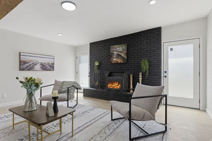 Living space featuring a black brick fireplace, wood-finish flooring, and recessed lighting