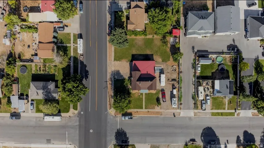 Corner lot property featuring a red-roofed residence, extensive paved street frontage, and a surrounding neighborhood context