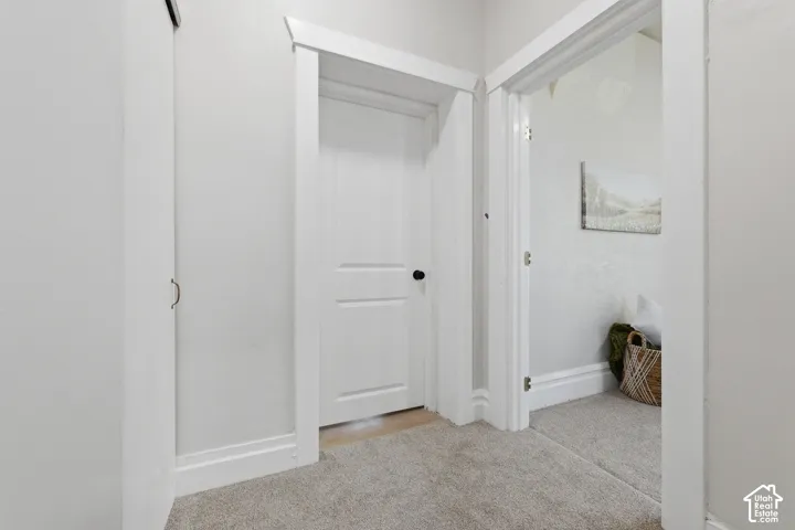 Hallway featuring light gray carpet flooring and white trim