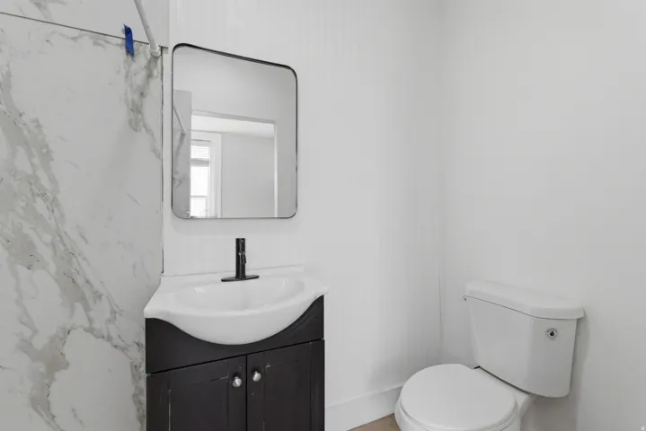 Modern bathroom vanity featuring a black cabinet, white countertop with integrated sink, and matte black faucet