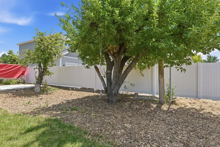 Backyard featuring established trees and a white privacy fence