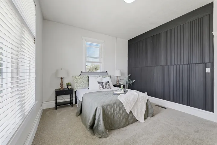 Bedroom featuring a striking dark accent wall with vertical paneling