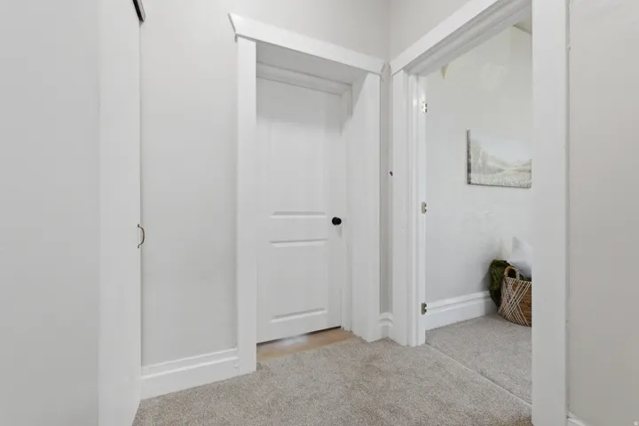 Hallway featuring light gray carpet flooring and white trim