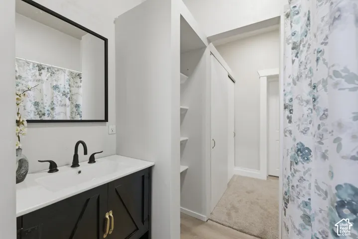 Bathroom vanity featuring a black cabinet with gold-toned hardware, white countertop, and matte black faucet
