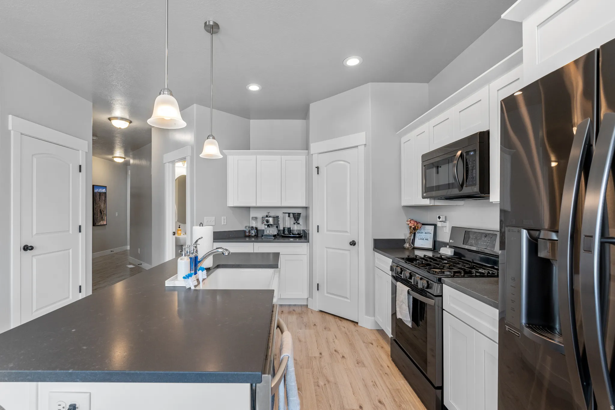 Contemporary kitchen featuring white cabinetry, dark countertops, and wood-finish flooring