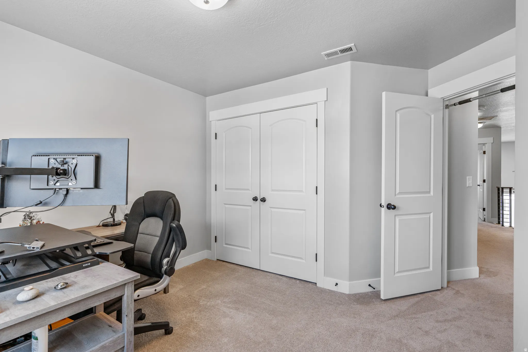 Carpeted room featuring a white two-panel arched door, white bi-fold closet doors, and white baseboards