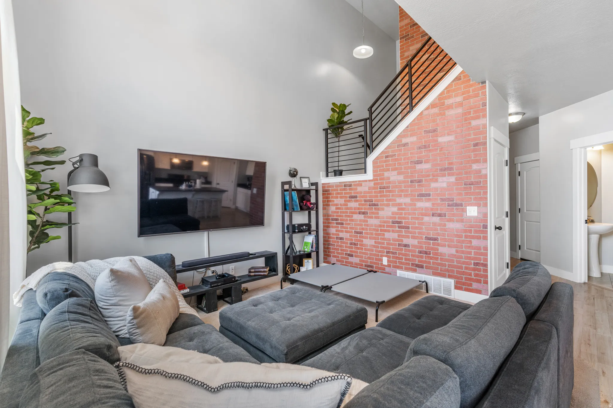 Vaulted ceilings highlight the accent brick wall and open staircase with metal railings