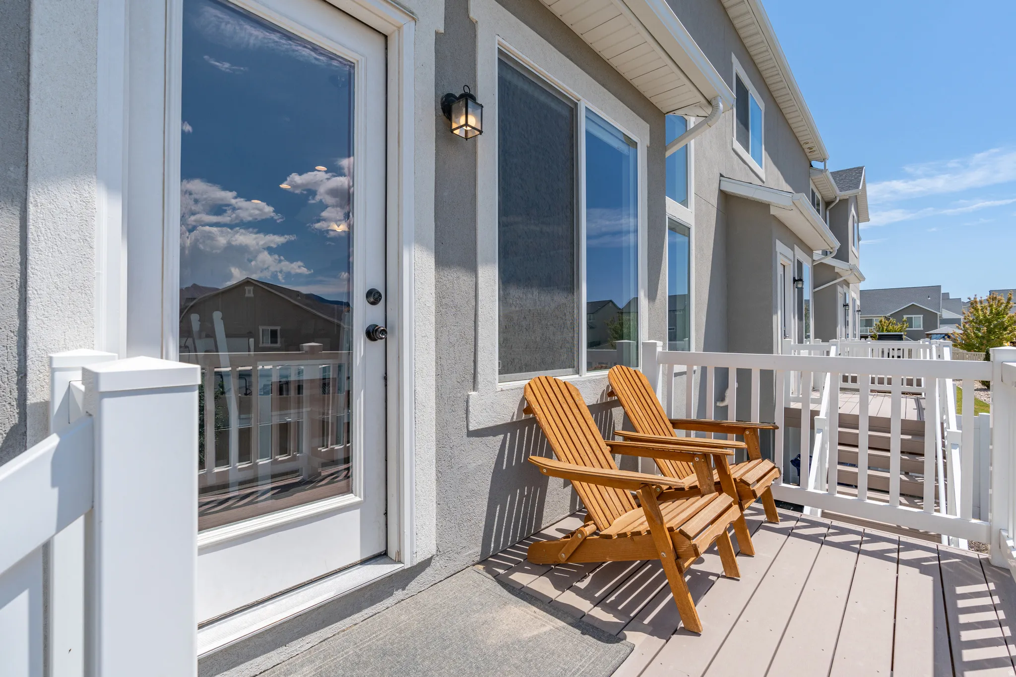 Exterior balcony featuring composite decking, white railing, and a full-light glass door