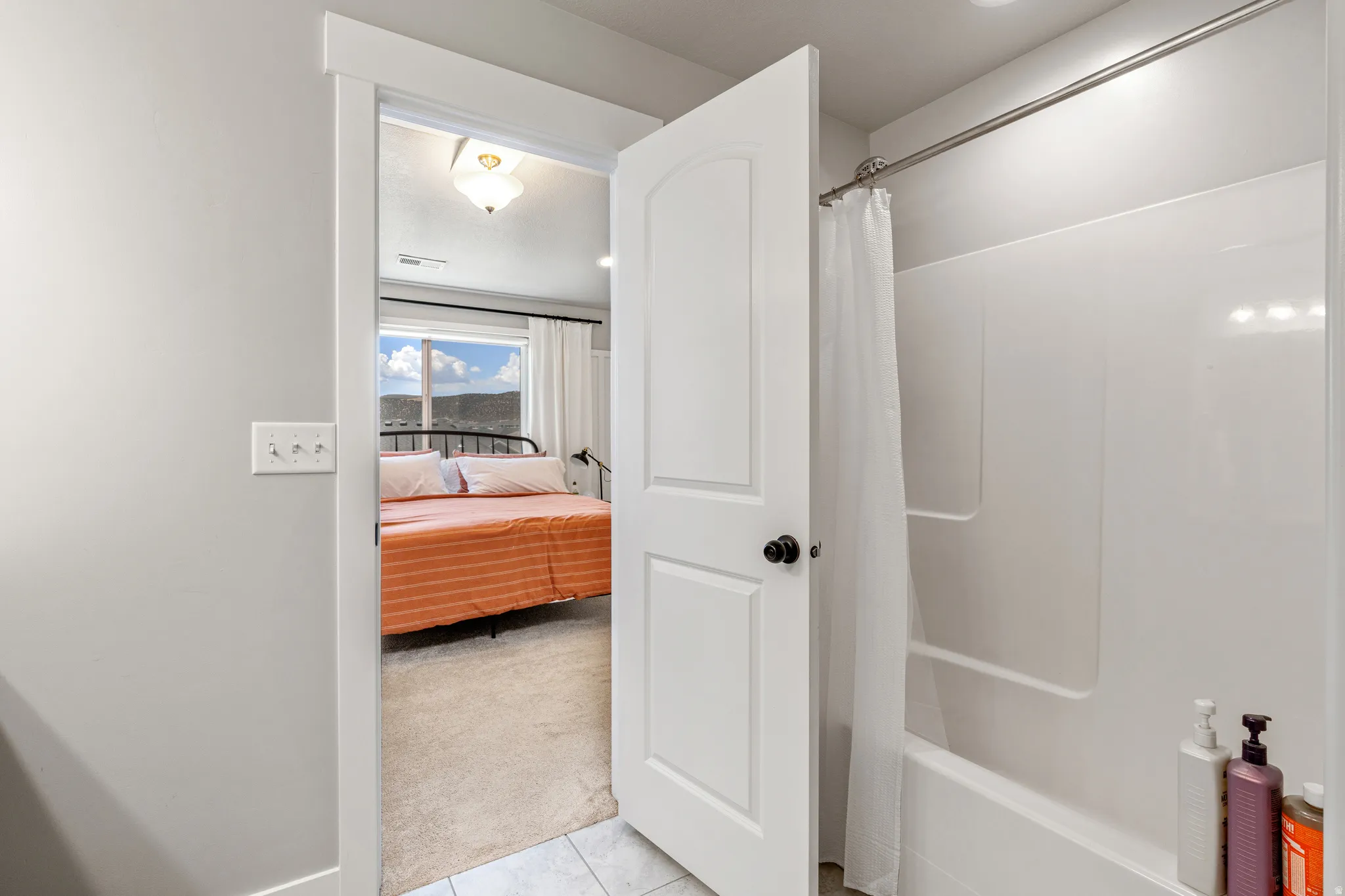 Bathroom featuring a white shower-over-tub combination with an integrated soap dish and a white shower curtain rod
