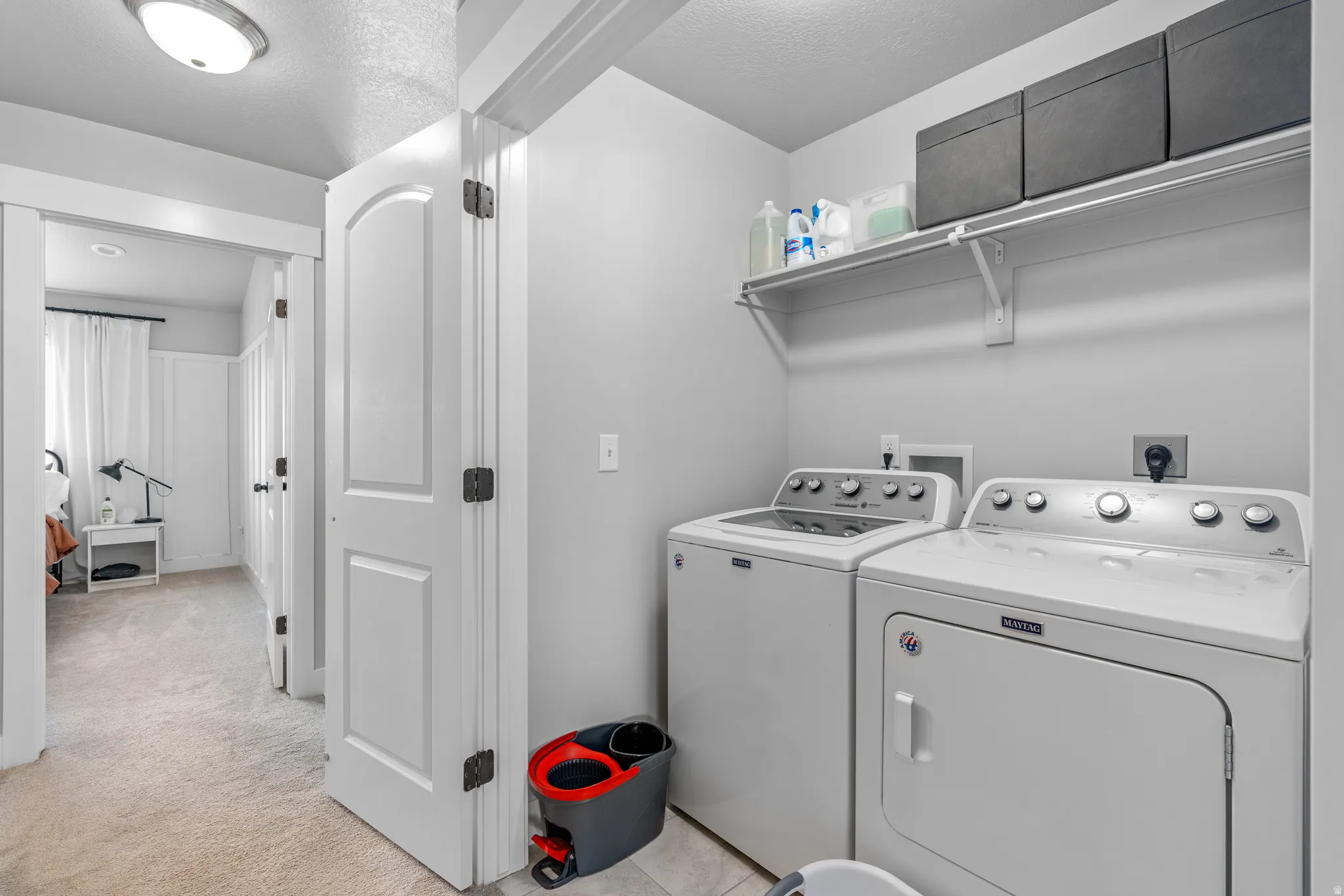 Dedicated laundry area featuring a washer and dryer, an overhead storage shelf, and light gray wall paint