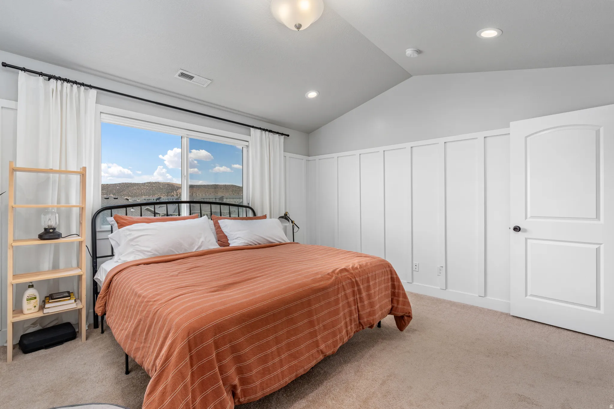 Spacious room featuring a large window, vaulted ceiling, recessed lighting, and board and batten wall detailing