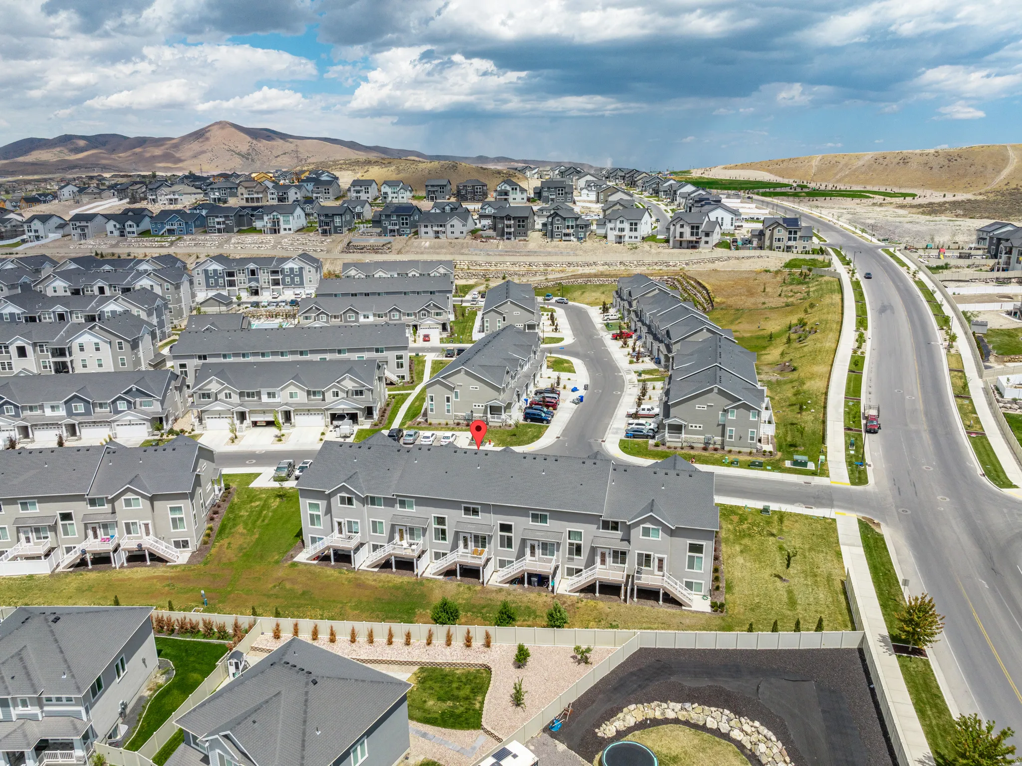Aerial perspective of a multi-unit residential development featuring gray-toned townhomes and single-family residences