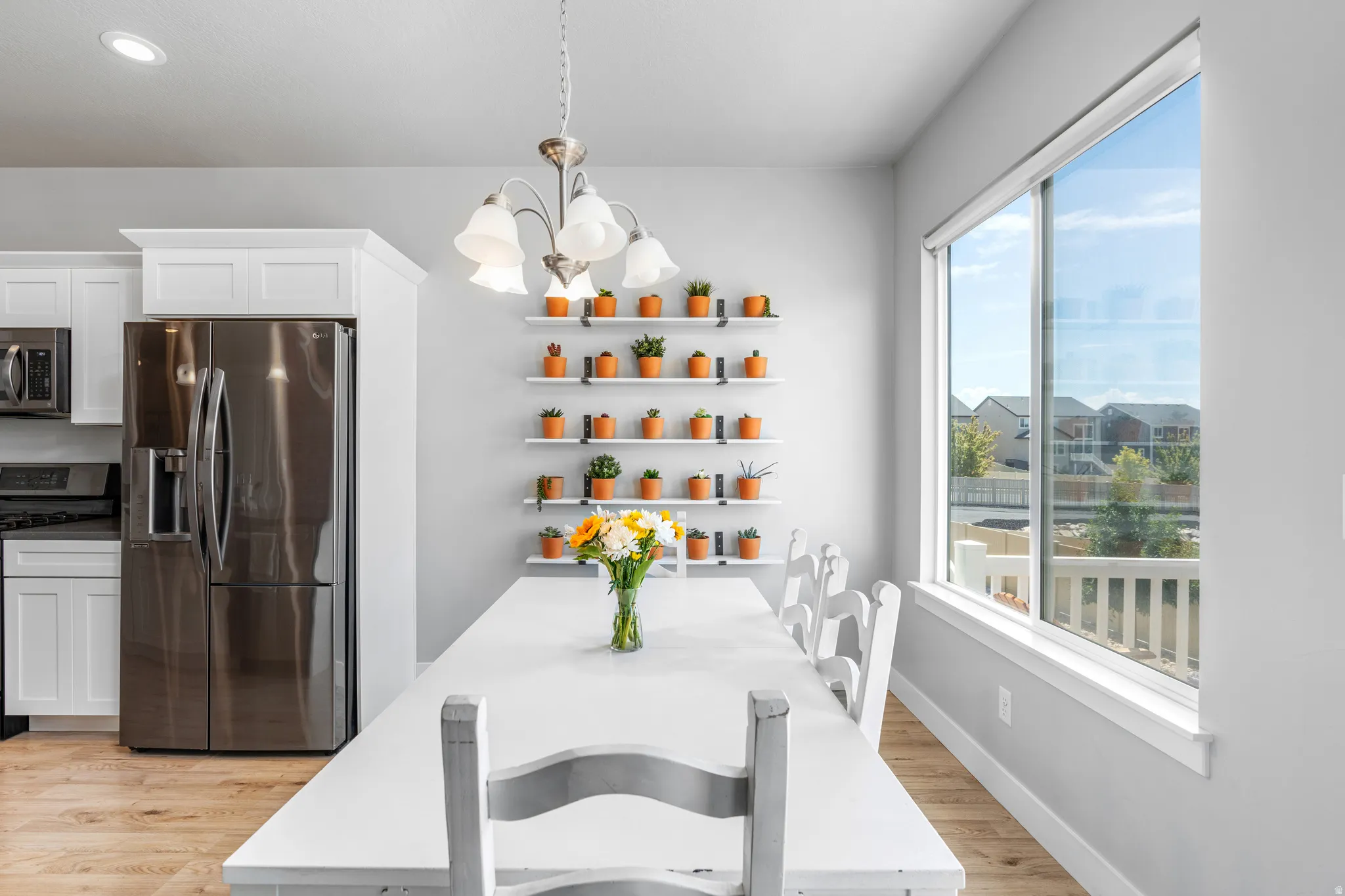 Bright dining area featuring a modern chandelier, extensive wall shelving, and a large picture window