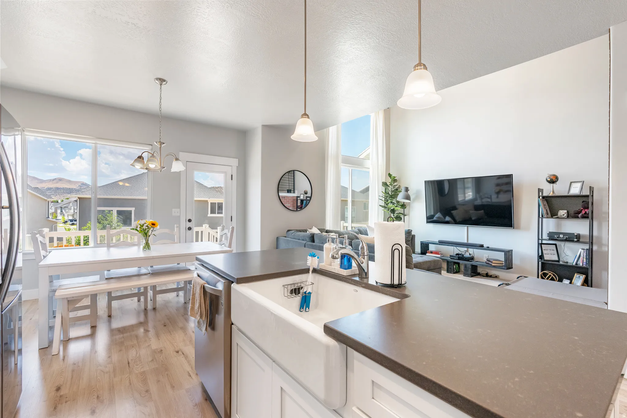 Open-concept living space featuring a spacious kitchen island with a farmhouse sink, stainless steel appliances, and wood-finish flooring