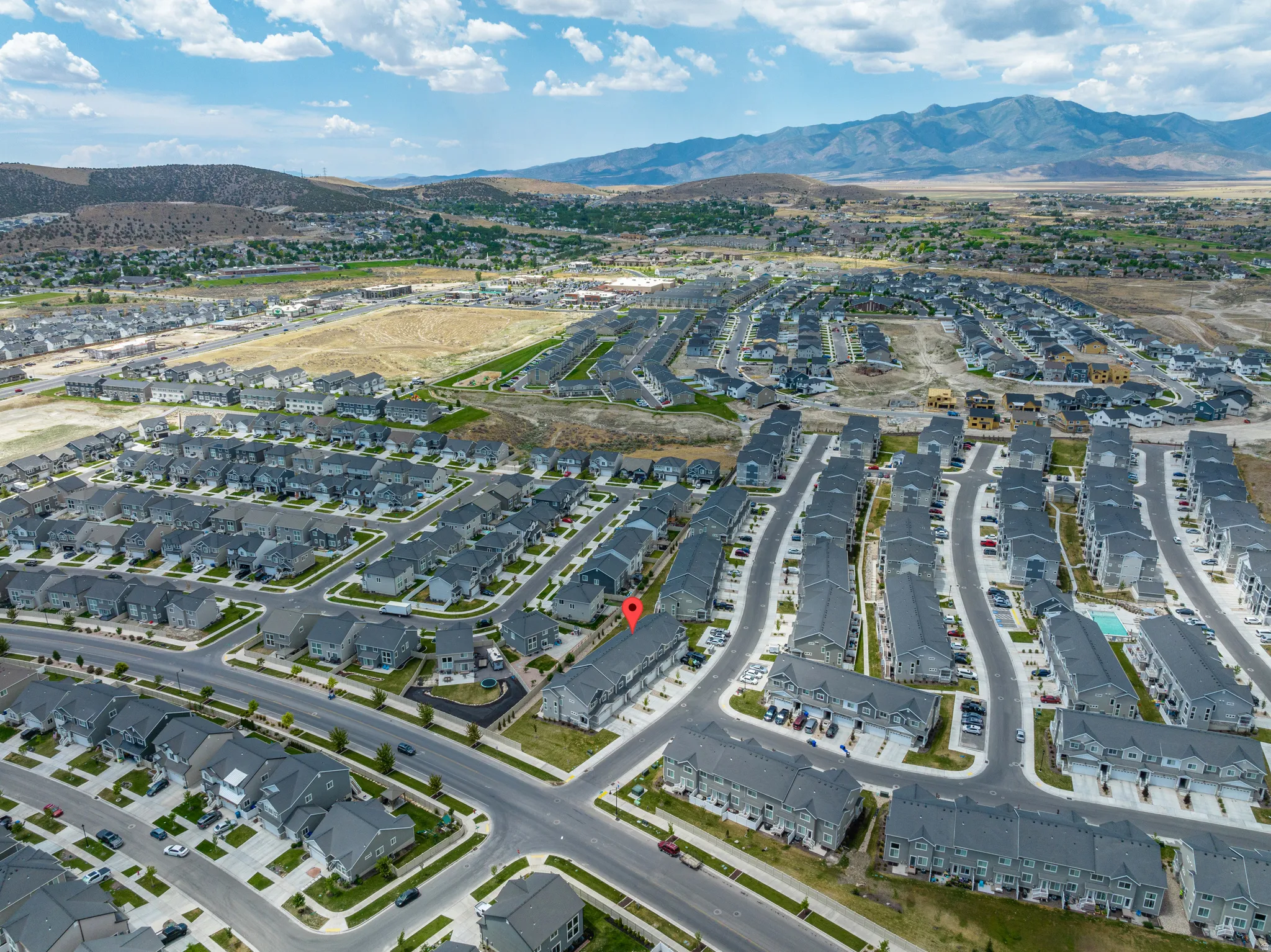Expansive residential community featuring a mix of single-family homes and townhomes, a structured street grid, and mountain backdrops