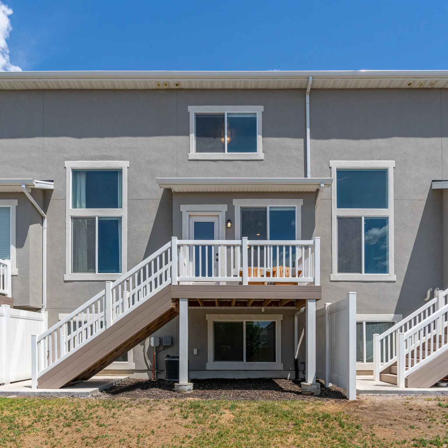 Rear exterior with a second-story deck, privacy fencing, and multiple windows