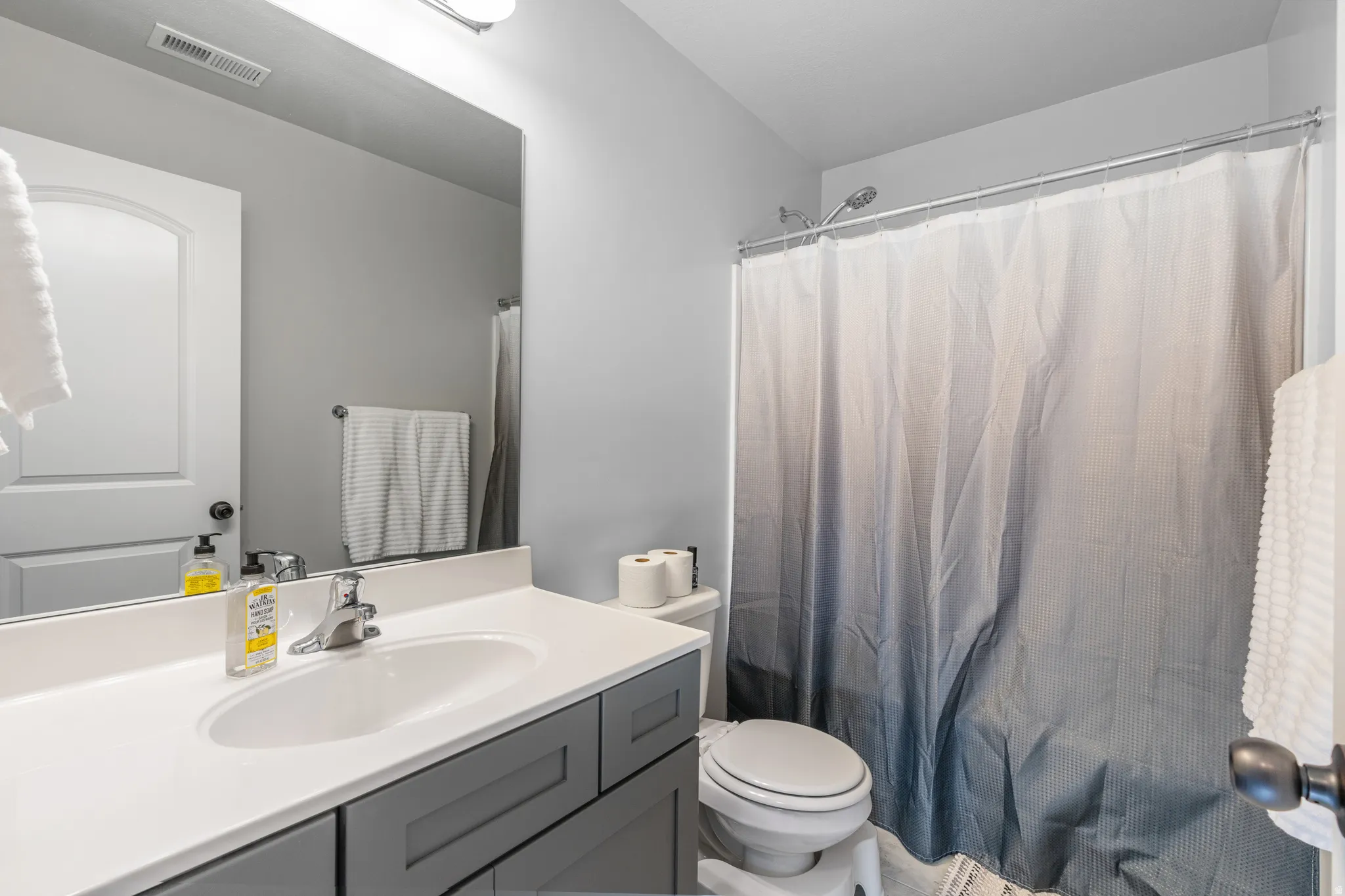 Bathroom featuring a vanity with a white countertop and gray cabinetry
